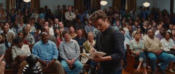 Movie still from “Footloose” (2011), directed by Craig Brewer – A man reading a book in front of an audience; Medium shot, High angle