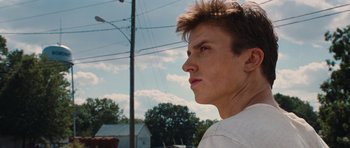 Movie still from “Footloose” (2011), directed by Craig Brewer – A young man looking to his left while standing on a street corner; Close Up shot, Low angle