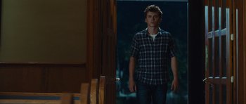 Movie still from “Footloose” (2011), directed by Craig Brewer – A man standing in front of a door in a room; Medium shot, Over the shoulder angle