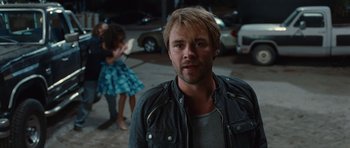 Movie still from “Footloose” (2011), directed by Craig Brewer – A man standing in front of two other people in a parking lot; Medium shot, Over the shoulder angle
