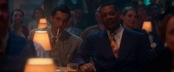 Movie still from “The United States vs. Billie Holiday” (2021), directed by Lee Daniels – A couple of men sitting at a table in front of a drink; Medium shot, Low angle