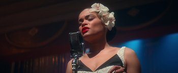 Movie still from “The United States vs. Billie Holiday” (2021), directed by Lee Daniels – A woman in a black and white dress with a microphone; Close Up shot, High angle