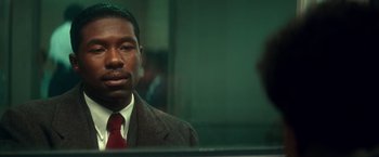Movie still from “The United States vs. Billie Holiday” (2021), directed by Lee Daniels – A man wearing a suit and tie in front of a mirror; Close Up shot, Over the shoulder angle