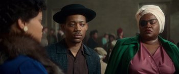 Movie still from “The United States vs. Billie Holiday” (2021), directed by Lee Daniels – A man wearing a black hat and a green jacket; Close Up shot, Over the shoulder angle