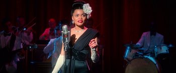 Movie still from “The United States vs. Billie Holiday” (2021), directed by Lee Daniels – A woman in a black dress holding a microphone; Medium shot, Over the shoulder angle