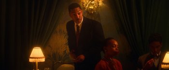 Movie still from “The United States vs. Billie Holiday” (2021), directed by Lee Daniels – A man in a suit and tie standing next to a woman in an orange dress; Medium shot, Low angle