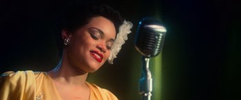 Movie still from “The United States vs. Billie Holiday” (2021), directed by Lee Daniels – A woman in a yellow dress and a microphone; Close Up shot, Low angle