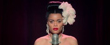 Movie still from “The United States vs. Billie Holiday” (2021), directed by Lee Daniels – A woman with a flower in her hair is holding a microphone; Close Up shot, Low angle