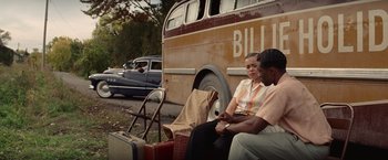 Movie still from “The United States vs. Billie Holiday” (2021), directed by Lee Daniels – Two people sitting next to each other in front of a bus; Medium shot, Over the shoulder angle