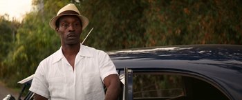 Movie still from “The United States vs. Billie Holiday” (2021), directed by Lee Daniels – A man standing next to a car with a straw hat on; Close Up shot, Over the shoulder angle