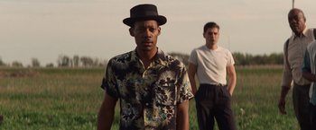 Movie still from “The United States vs. Billie Holiday” (2021), directed by Lee Daniels – A man in a hat standing next to another man in a field; Medium shot, Low angle