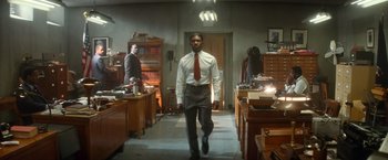 Movie still from “The United States vs. Billie Holiday” (2021), directed by Lee Daniels – A man in a suit and tie walking through a room; Wide shot, Low angle