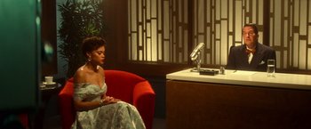 Movie still from “The United States vs. Billie Holiday” (2021), directed by Lee Daniels – A woman sitting in front of a microphone on top of a red chair; Medium shot, High angle