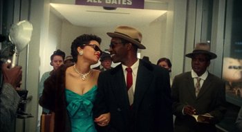 Movie still from “The United States vs. Billie Holiday” (2021), directed by Lee Daniels – A man and a woman are standing in front of a crowd of onlookers; Medium shot, Low angle