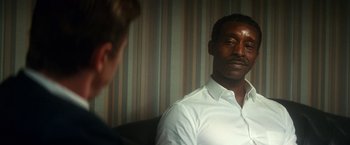 Movie still from “The United States vs. Billie Holiday” (2021), directed by Lee Daniels – A man wearing a white shirt is talking to another man in front of him; Close Up shot, Over the shoulder angle