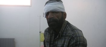 Movie still from “For Sama” (2019), directed by Edward Watts – A man with bandages on his head and a plaid shirt; Close Up shot, Over the shoulder angle