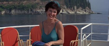 Movie still from “For Your Eyes Only” (1981), directed by John Glen – A woman in a blue dress sitting on a red chair; Medium shot, High angle