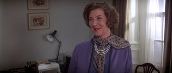 Movie still from “For Your Eyes Only” (1981), directed by John Glen – An older woman wearing a purple jacket and a polka dot neck tie; Close Up shot, Over the shoulder angle