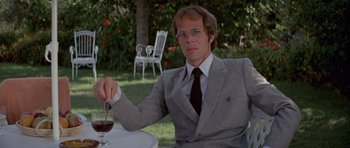 Movie still from “For Your Eyes Only” (1981), directed by John Glen – A man sitting at a table with a glass of wine; Medium shot, Low angle