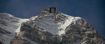 Movie still from “For Your Eyes Only” (1981), directed by John Glen – A person standing on top of a snow covered mountain; Extreme Wide shot, Low angle