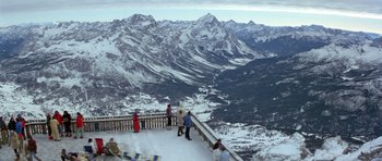 Movie still from “For Your Eyes Only” (1981), directed by John Glen – A group of people standing on top of a snow covered slope; Extreme Wide shot, High angle