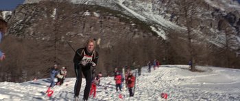 Movie still from “For Your Eyes Only” (1981), directed by John Glen – A person skiing down a hill with other skiers in the background; Wide shot, Low angle