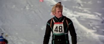 Movie still from “For Your Eyes Only” (1981), directed by John Glen – A man in black and white ski suit standing in the snow; Medium shot, Over the shoulder angle