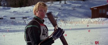 Movie still from “For Your Eyes Only” (1981), directed by John Glen – A man holding a pair of skis on a snowy slope; Medium shot, Low angle
