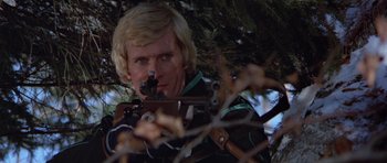 Movie still from “For Your Eyes Only” (1981), directed by John Glen – A man holding a gun while standing next to a tree; Close Up shot, Low angle