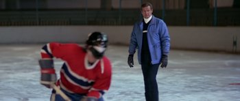 Movie still from “For Your Eyes Only” (1981), directed by John Glen – A man standing on the ice with a hockey player; Medium shot, Over the shoulder angle
