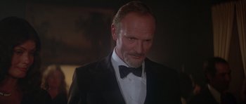 Movie still from “For Your Eyes Only” (1981), directed by John Glen – A person wearing a suit and bow tie; Close Up shot, Low angle
