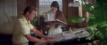 Movie still from “For Your Eyes Only” (1981), directed by John Glen – A man and a woman looking at a book; Medium shot, High angle