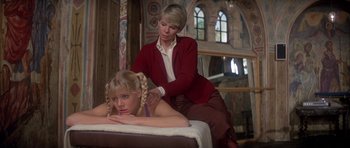 Movie still from “For Your Eyes Only” (1981), directed by John Glen – A woman in a red jacket is getting a massage from another woman in a red jacket; Medium shot, Low angle