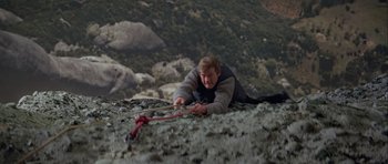 Movie still from “For Your Eyes Only” (1981), directed by John Glen – A man on the ground with a rope on a mountain; Wide shot, High angle