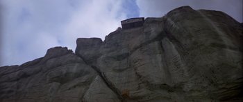 Movie still from “For Your Eyes Only” (1981), directed by John Glen – A building on a cliff with a sky background; Extreme Wide shot, Low angle