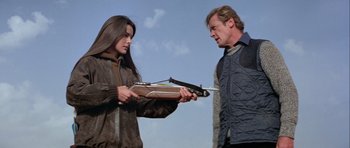 Movie still from “For Your Eyes Only” (1981), directed by John Glen – A man and a woman are holding a crossbow; Medium shot, Over the shoulder angle