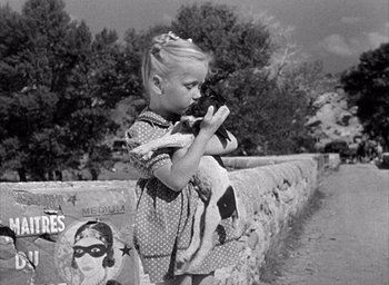 Movie still from “Forbidden Games” (1952), directed by René Clément – A little girl is holding a dog in her arms; Medium shot, High angle