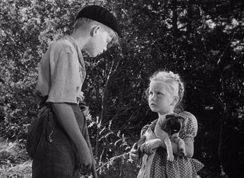 Movie still from “Forbidden Games” (1952), directed by René Clément – A boy and a little girl standing next to each other in front of a tree; Medium shot, Over the shoulder angle