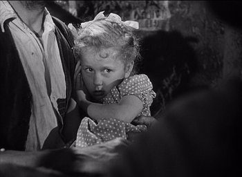 Movie still from “Forbidden Games” (1952), directed by René Clément – A little girl sitting on a man's lap; Close Up shot, High angle