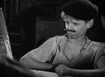 Movie still from “Forbidden Games” (1952), directed by René Clément – A young man with a pipe in his mouth sitting at a table; Close Up shot, High angle