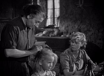 Movie still from “Forbidden Games” (1952), directed by René Clément – An old photo of a woman and a man combing a little girl's hair; Medium shot, Over the shoulder angle