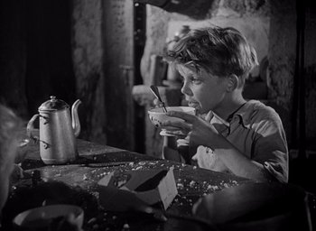 Movie still from “Forbidden Games” (1952), directed by René Clément – A young boy sitting at a table with a bowl of cereal; Medium shot, High angle