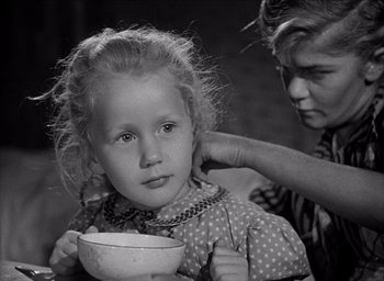 Movie still from “Forbidden Games” (1952), directed by René Clément – An older woman holding a bowl while a young girl holds a bowl in front of her face; Close Up shot, Over the shoulder angle