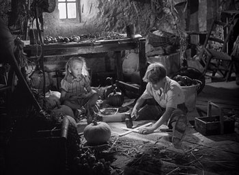 Movie still from “Forbidden Games” (1952), directed by René Clément – Two people sitting on the ground in a room; Wide shot, High angle