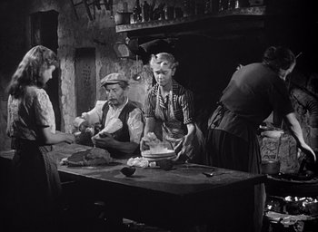 Movie still from “Forbidden Games” (1952), directed by René Clément – An old photo of a group of people preparing food; Medium shot, High angle