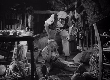 Movie still from “Forbidden Games” (1952), directed by René Clément – An old photo of a group of people sitting and standing around; Wide shot, High angle