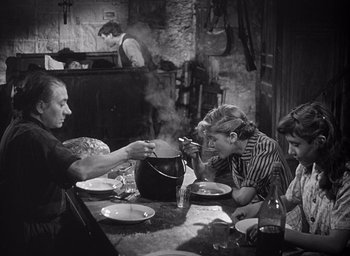 Movie still from “Forbidden Games” (1952), directed by René Clément – An old photo of a family sitting at a dinner table; Medium shot, High angle