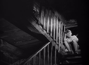 Movie still from “Forbidden Games” (1952), directed by René Clément – A young boy sitting on top of a set of stairs; Wide shot, High angle