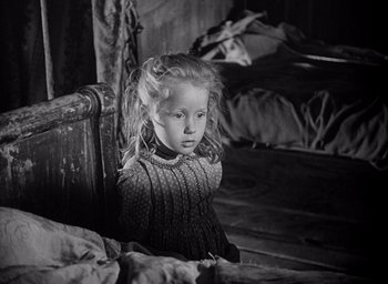 Movie still from “Forbidden Games” (1952), directed by René Clément – A little girl sitting on a chair in a room; Medium shot, High angle