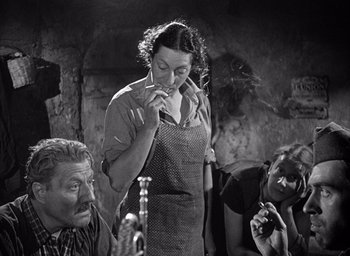 Movie still from “Forbidden Games” (1952), directed by René Clément – An old photo of a woman smoking a cigarette with two other people; Medium shot, High angle